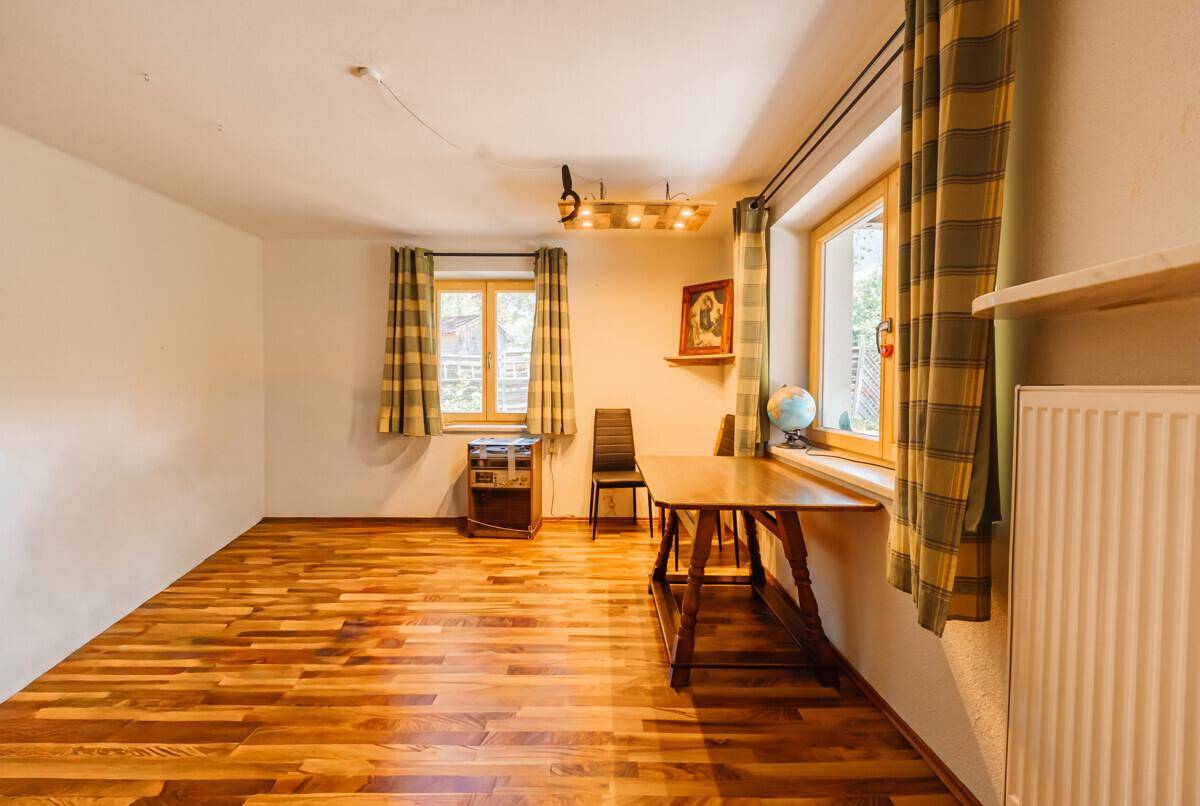Geräumiger, heller Raum mit Holzboden und zwei Fenstern, bereit zur individuellen Gestaltung.