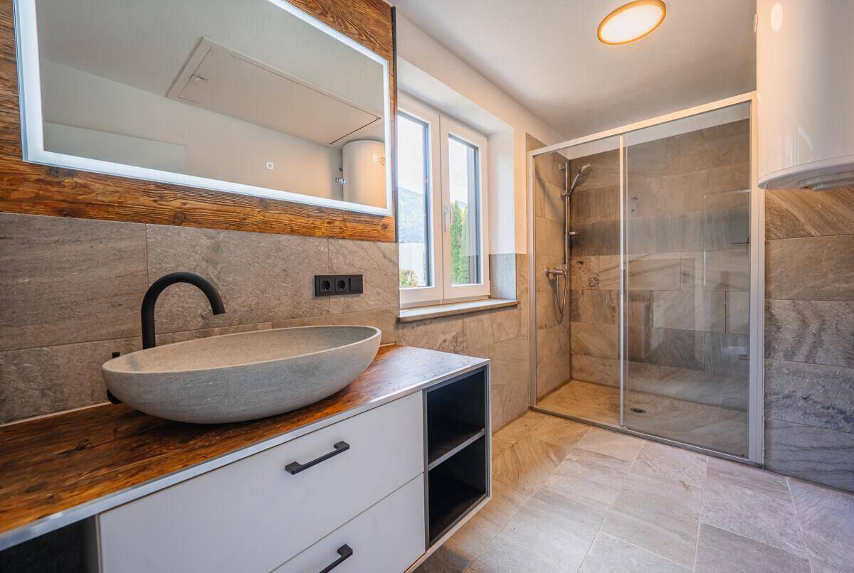 Modernes Badezimmer mit begehbarer Dusche, Aufsatzwaschbecken und Holzdetails.