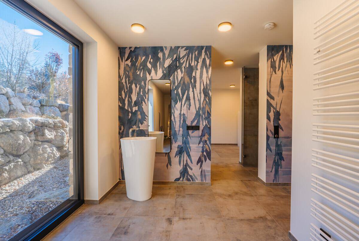Heller Flur mit modernem Waschbecken, dekorativer Tapete und großem Fenster.