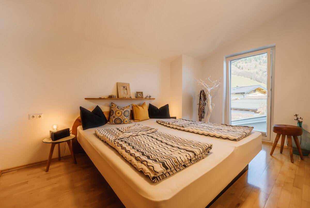 Helles Schlafzimmer mit Holzboden, Doppelbett und großem Fenster mit Blick auf die Landschaft.