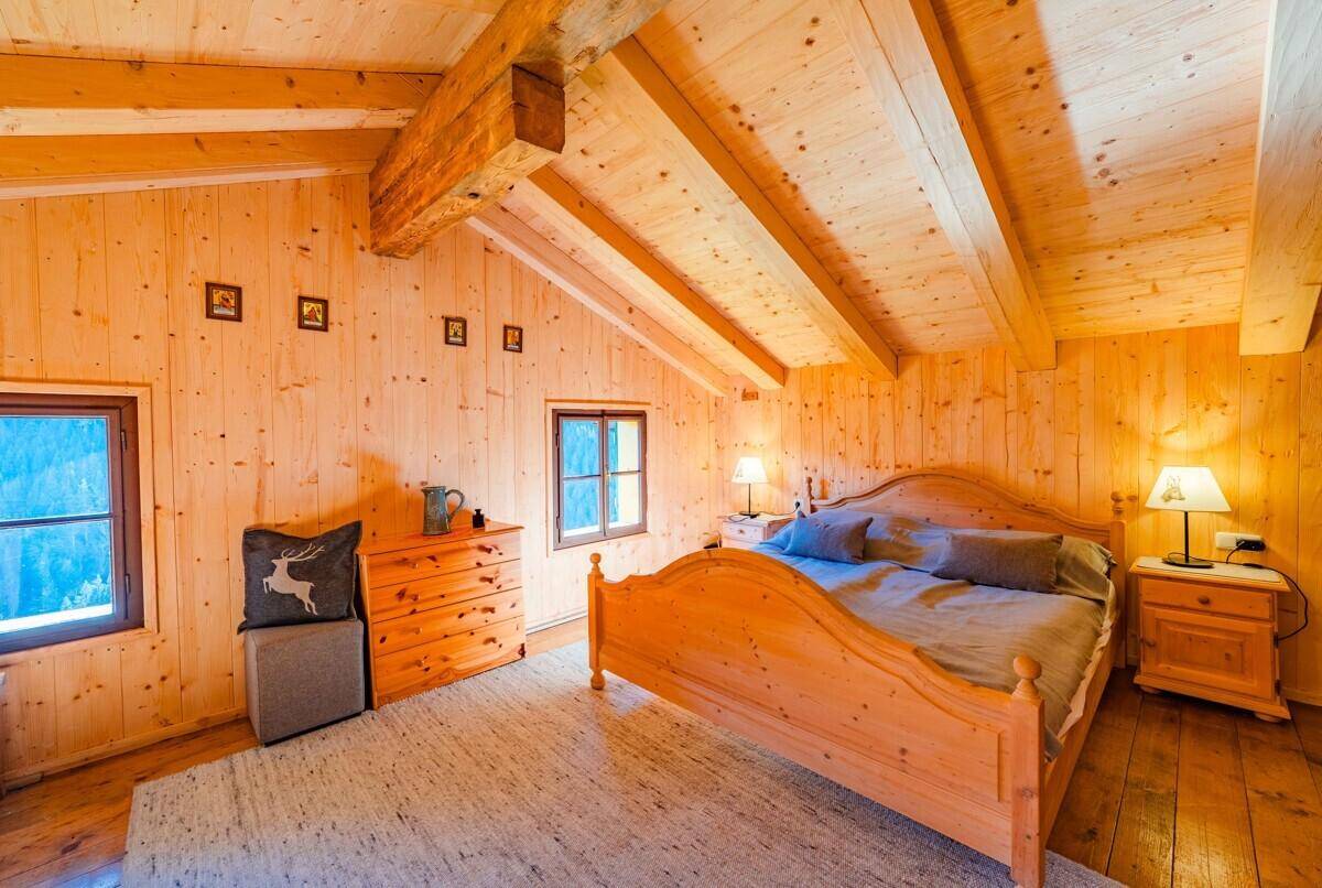 Gemütliches Schlafzimmer mit Holztäfelung, Dachschräge und traditionellem Holzbett.