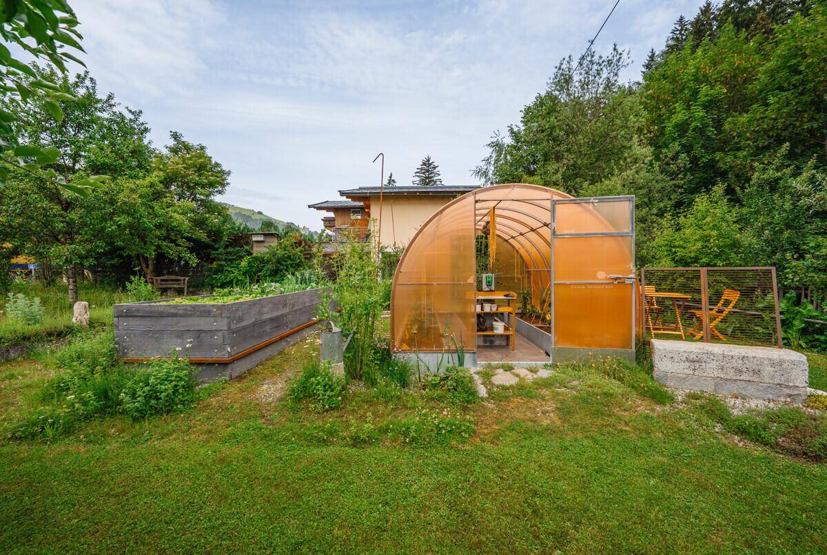 Nutzgarten mit Gewächshaus und Hochbeeten, perfekt für den Anbau von Gemüse und Kräutern.