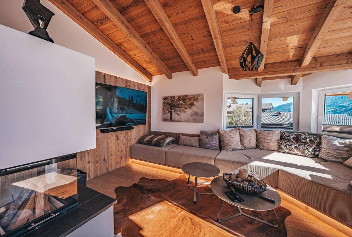 Gemütliches Wohnzimmer mit Holzwänden, integriertem Sofa, Kamin und Fernseher.