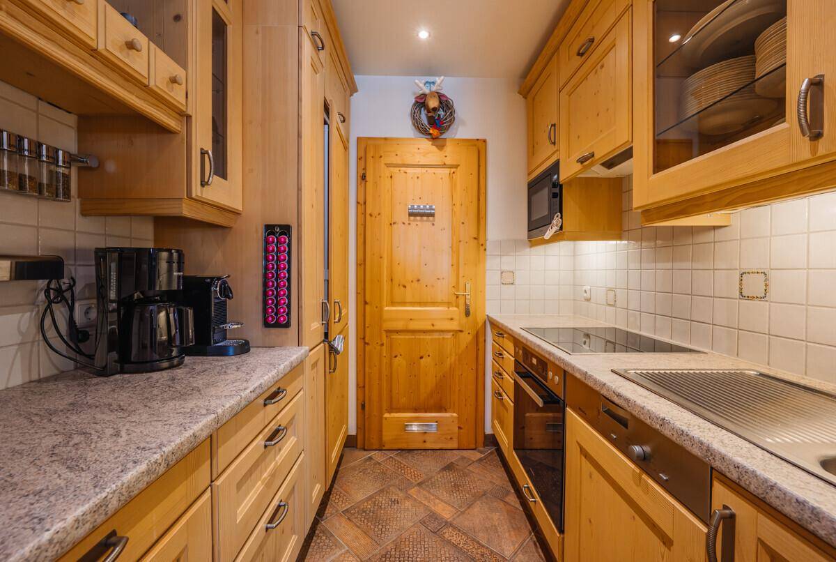 Funktionale Küche mit Holzschränken, Granit-Arbeitsplatten und integrierten Geräten.