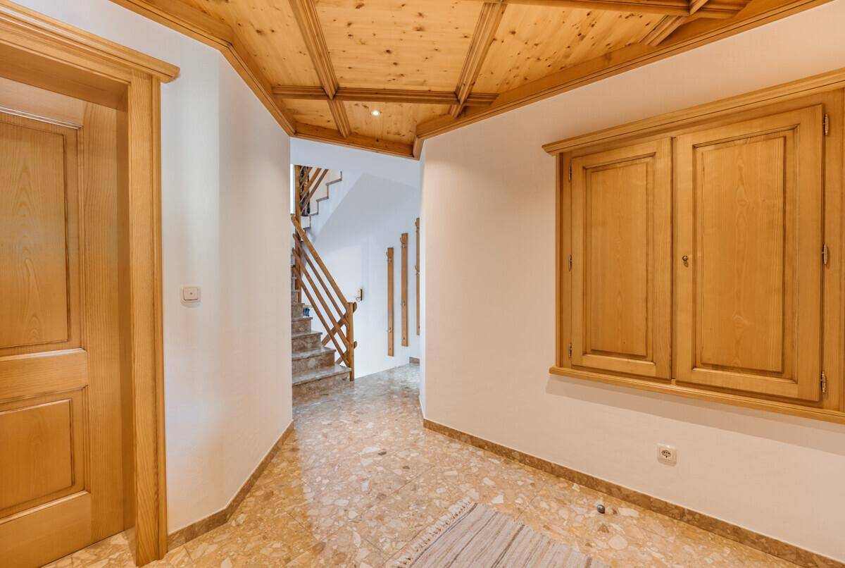 Heller Flur mit traditioneller Holzdecke, Terrazzoboden und Zugang zur Treppe.