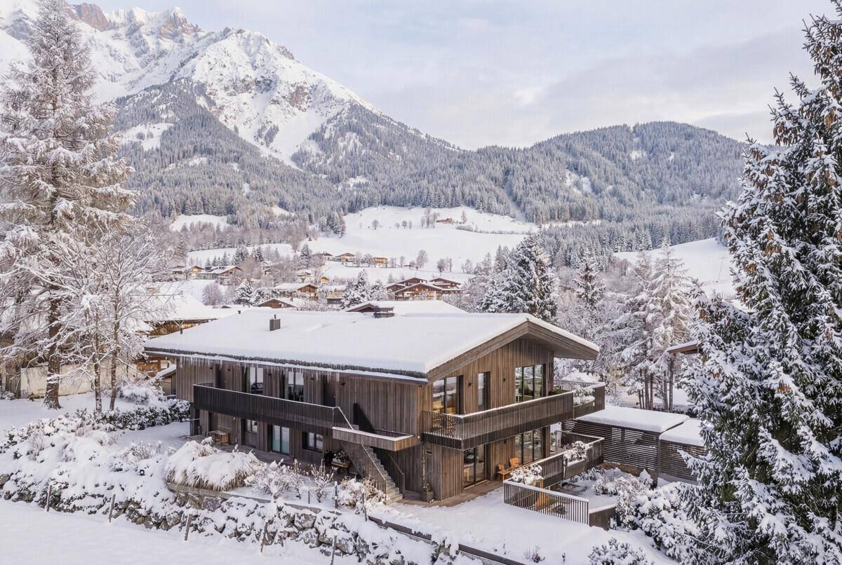 Traditionelles Chalet in verschneiter Winterlandschaft am Tag mit klarem Bergblick.