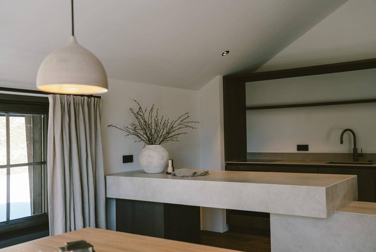 Moderne Küche mit minimalistischem Design, Stein-Arbeitsplatte und stilvoller Pendelleuchte.