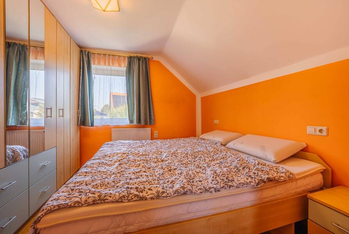Dachgeschoss-Schlafzimmer mit orangefarbenen Wänden, Doppelbett und Einbauschränken.