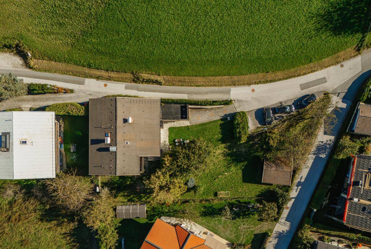Direkte Draufsicht auf das Haus mit Satteldach, Gartenbereich und angrenzender Zufahrtsstraße.