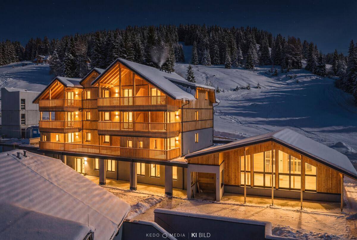 Beleuchteter Gebäudekomplex in der Winternacht, der eine warme und einladende Atmosphäre schafft.