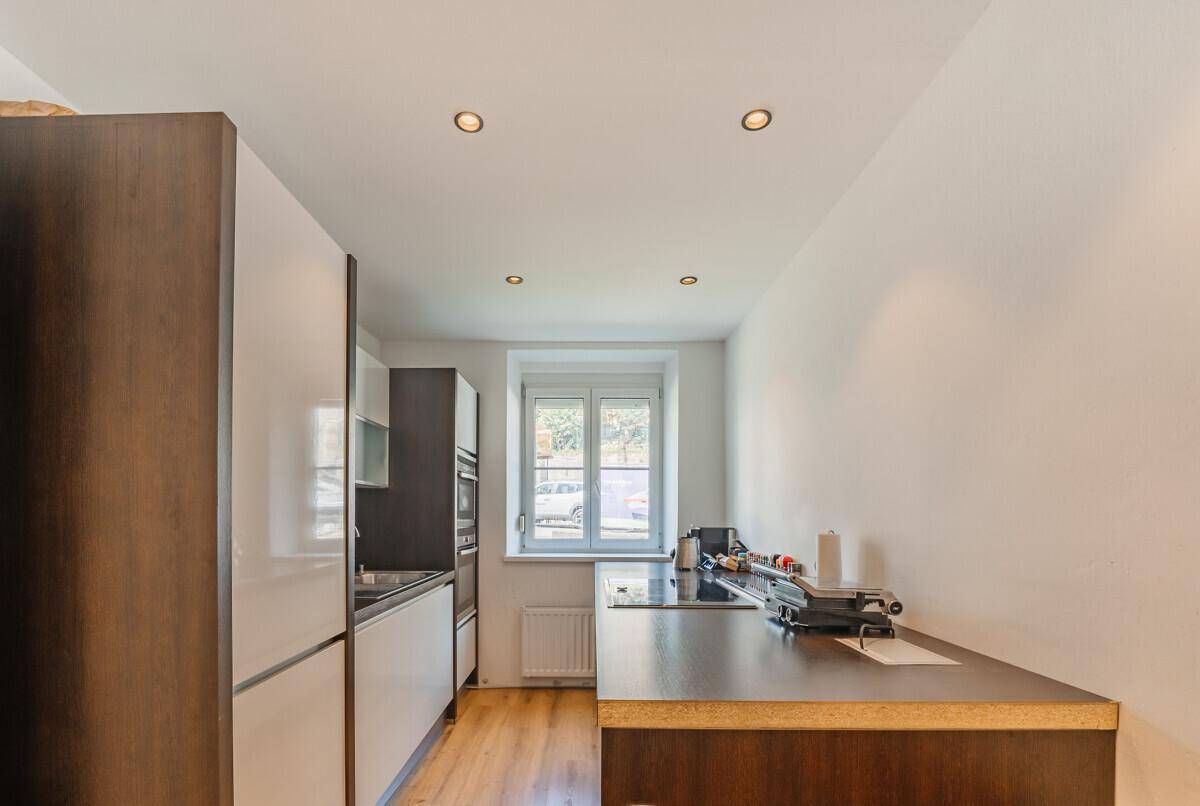 Moderne Küche mit dunklen Arbeitsplatten, weißen und braunen Schränken und Fenster.