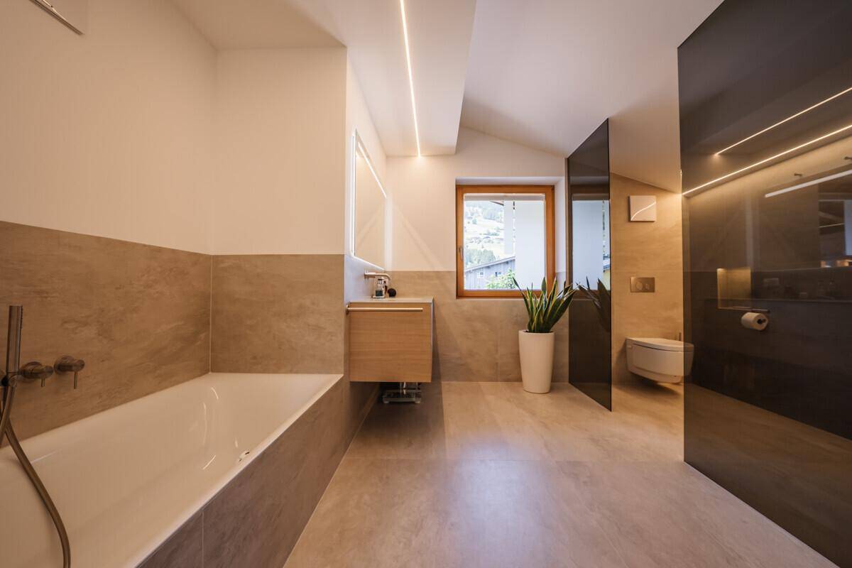 Modernes Badezimmer mit Badewanne, Waschtisch und Fenster für natürliches Licht.