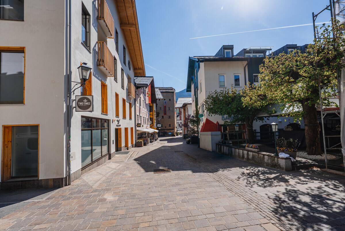 Malerische Gasse mit traditionellen Gebäuden, gepflastertem Boden und klarem Himmel.