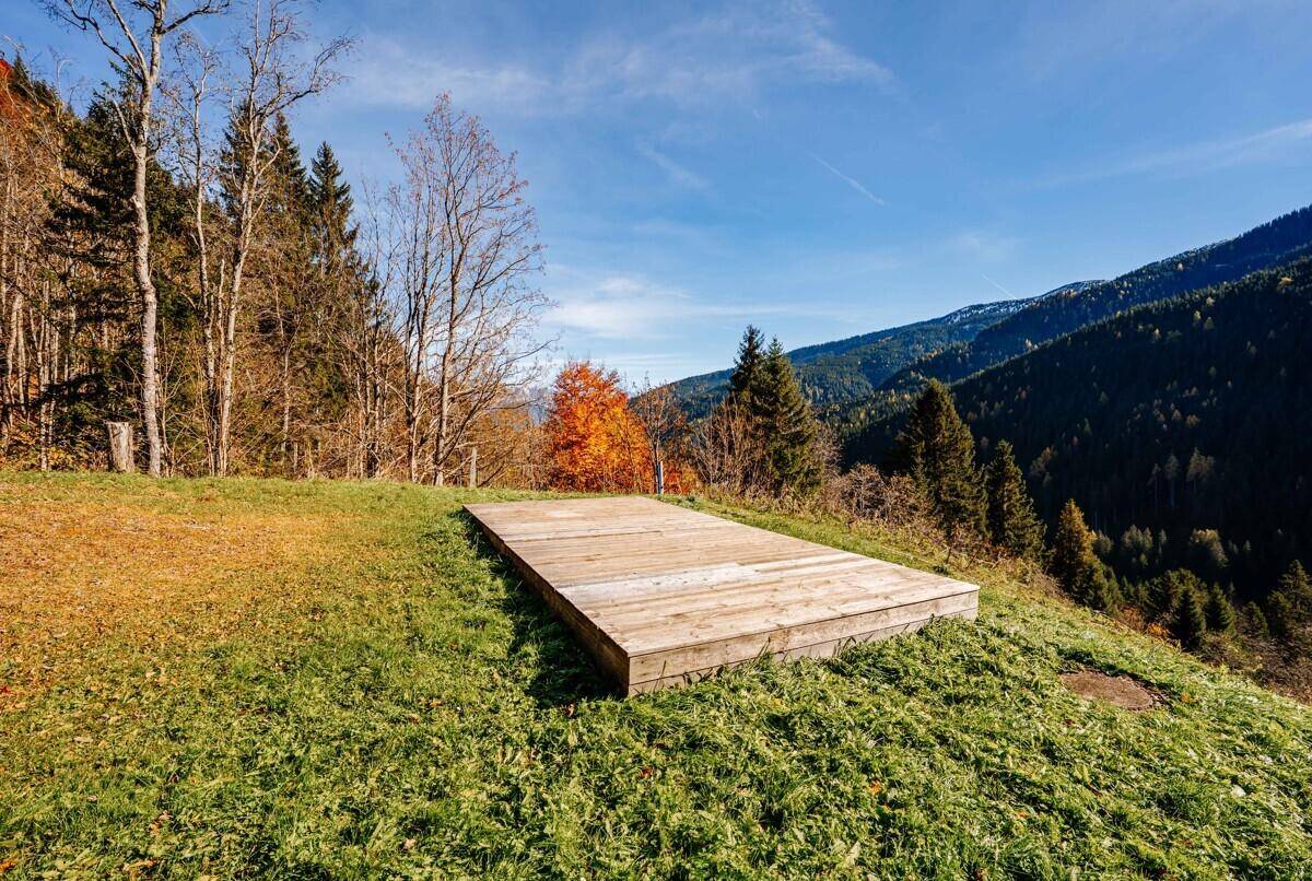 Holzplattform im Garten mit weitem Blick auf die umliegende Berglandschaft.