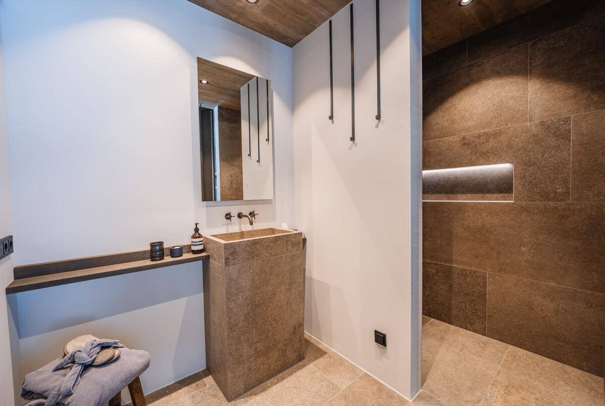Modernes Badezimmer mit Steinfliesen, Einzelwaschbecken und begehbarer Dusche.