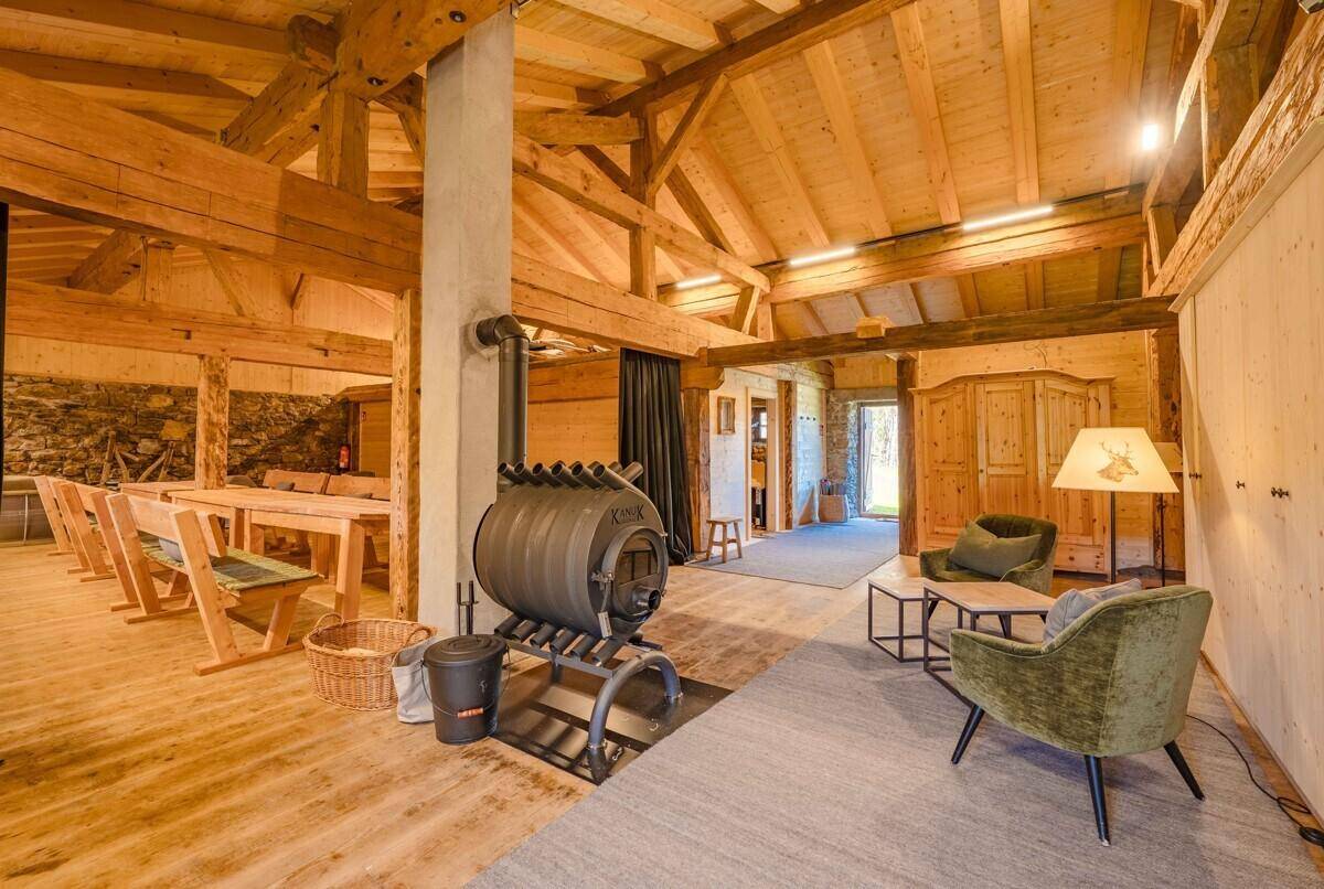 Geräumiger Wohnbereich mit Holzbalken, modernem Holzofen und gemütlichen Sitzgelegenheiten.