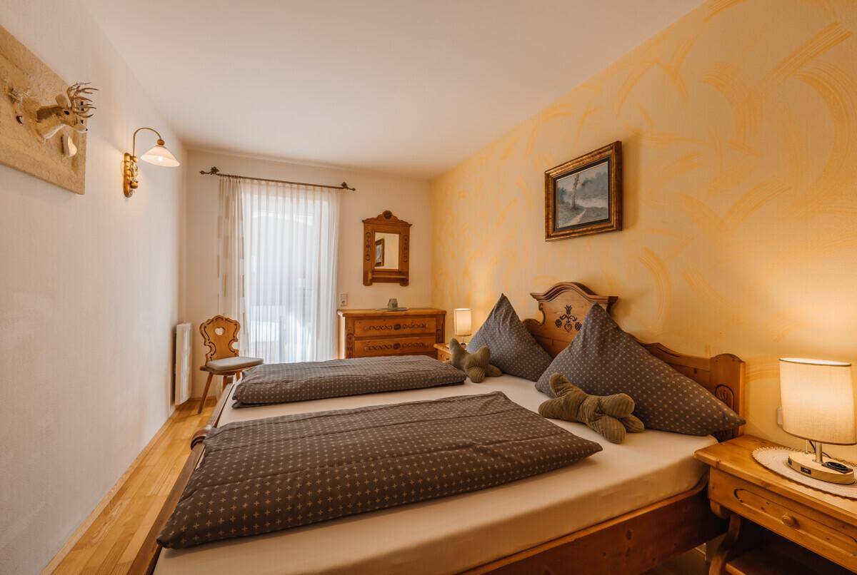Helles Schlafzimmer mit zwei Einzelbetten, Holzmöbeln und traditioneller Dekoration.