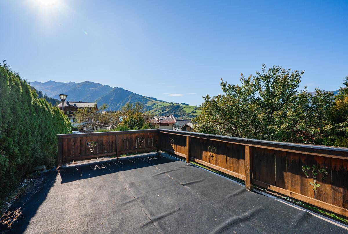 Geräumige, unmöblierte Terrasse mit Holzbalkonbrüstung und weitem Blick auf die umliegende Berglandschaft.