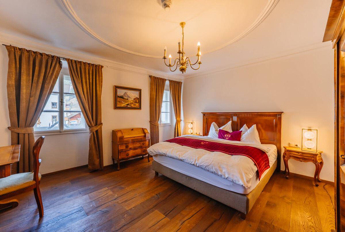 Geräumiges Schlafzimmer mit Doppelbett, Holzboden, Stuckdecke und traditionellen Holzmöbeln.