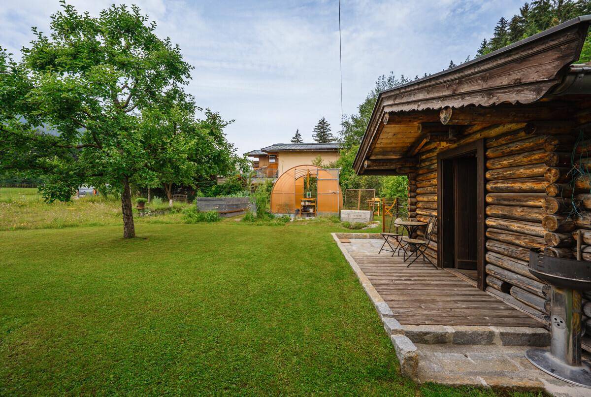 Grüner Gartenbereich mit Rasenfläche, Obstbaum und einer kleinen Holzhütte, ideal zur Entspannung.