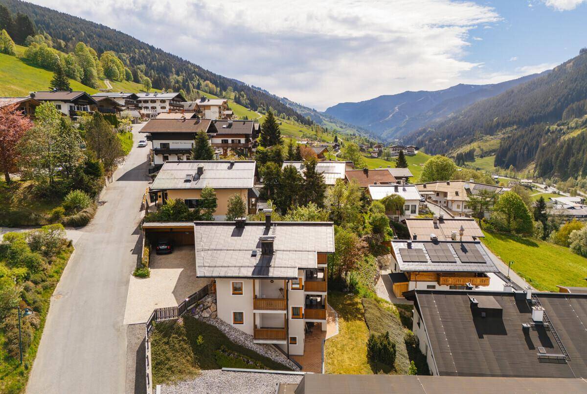 Luftaufnahme eines Bergdorfes in einem grünen Tal mit vielen Häusern und Bergen im Hintergrund.