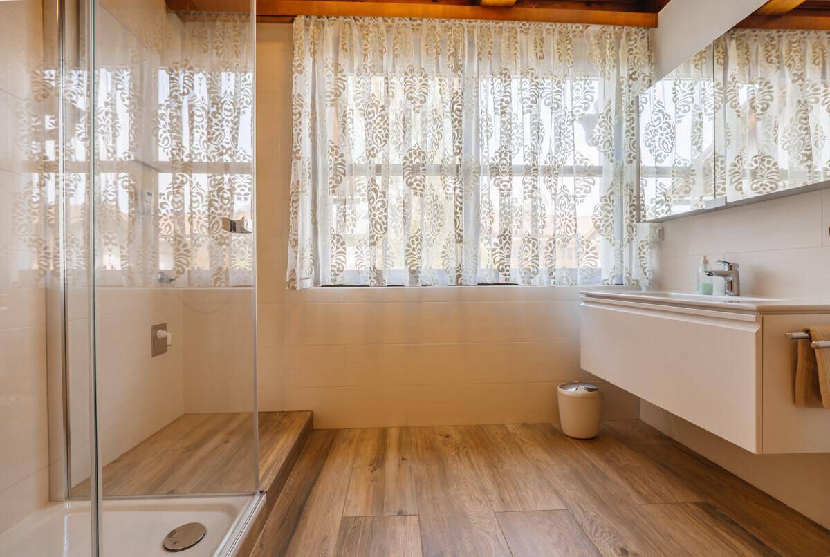 Modernes Badezimmer mit begehbarer Dusche, schwebendem Waschtisch und Fenster.