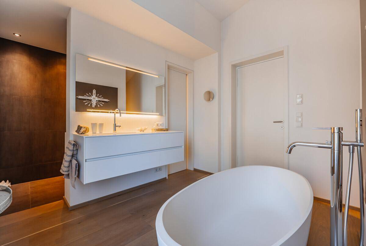 Elegantes Badezimmer mit freistehender Badewanne, schwebendem Waschtisch und großem Spiegel, sehr modern.