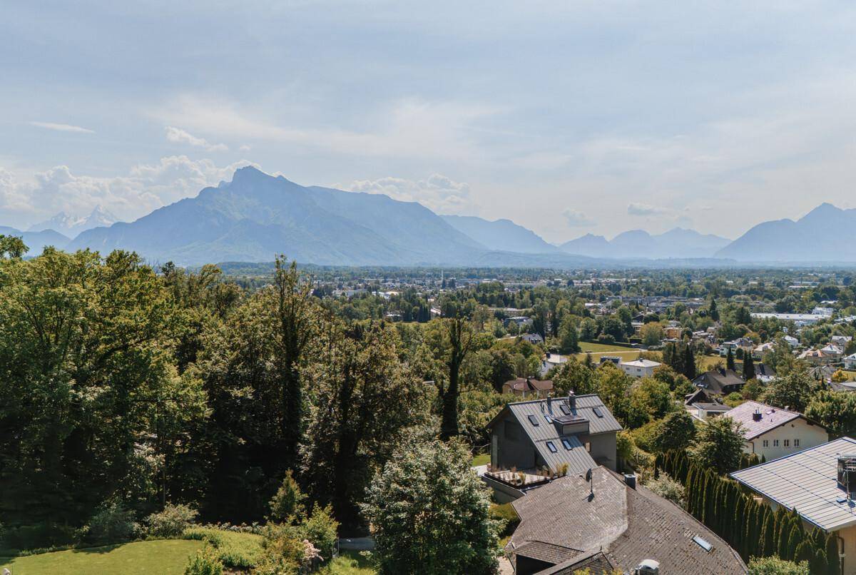 Weitläufiger Blick über die Stadt und die umliegende Berglandschaft an einem sonnigen Tag.