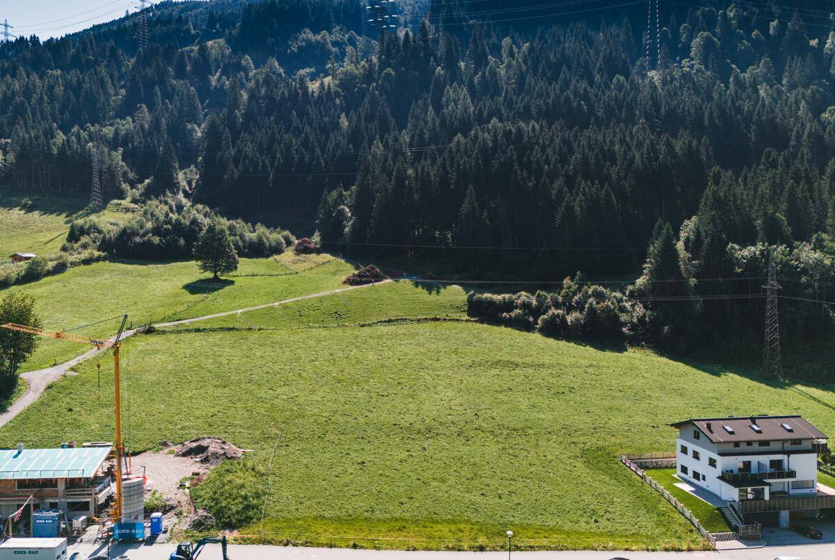 Panoramische Luftaufnahme einer ländlichen Landschaft mit Wald, Wiesen, einem Bauprojekt und Wohnhäusern.