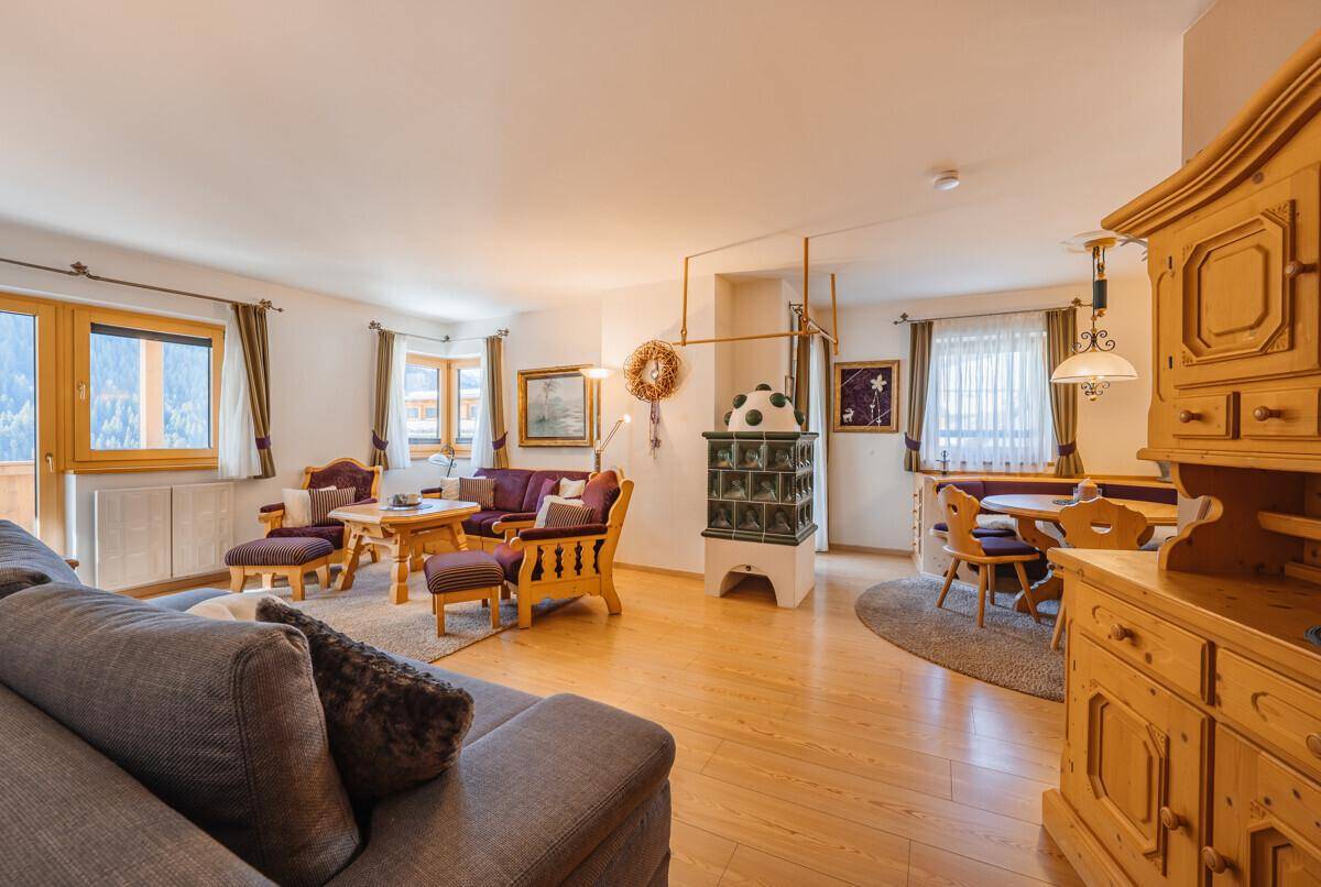 Traditioneller Wohn- und Essbereich mit Holzboden, Kachelofen und gemütlichen Holzmöbeln.