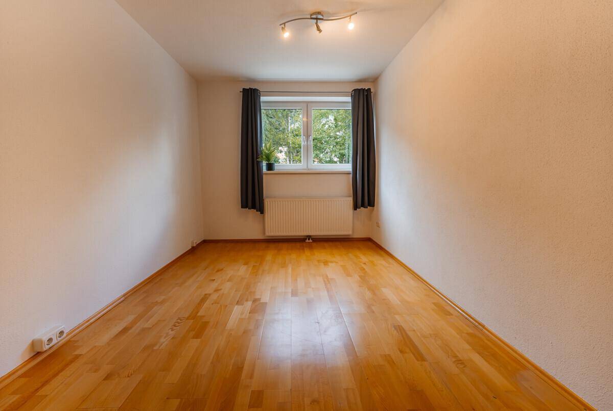 Freundliches Zimmer mit Holzboden und Fenster, vielseitig nutzbar als Schlaf- oder Arbeitszimmer.