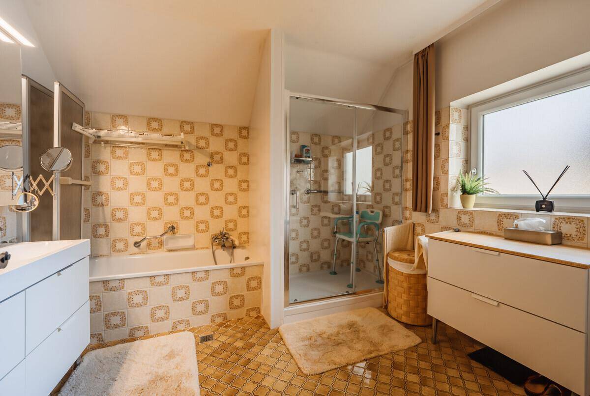 Badezimmer im Stil der 80er Jahre mit gemusterten Fliesen, Badewanne und separater Dusche.