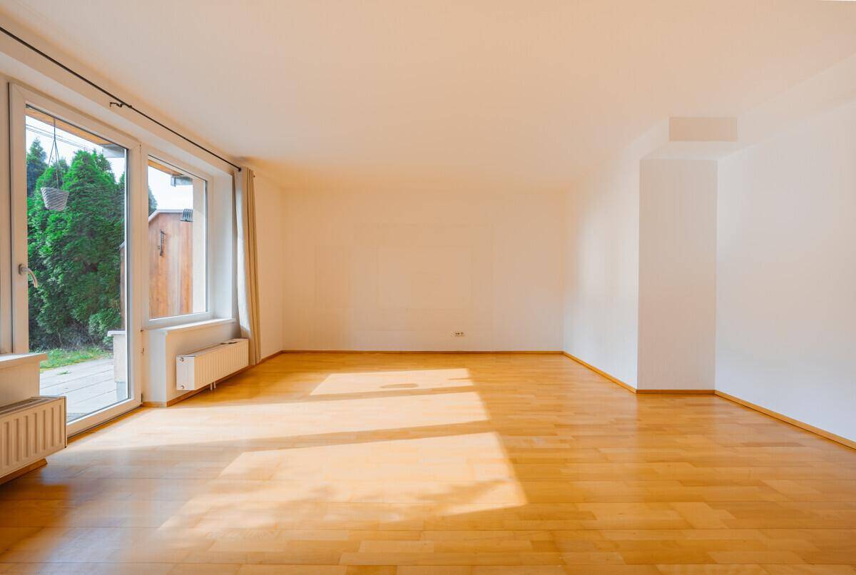 Lichtdurchflutetes Wohnzimmer mit Holzboden und direktem Zugang zum Gartenbereich.