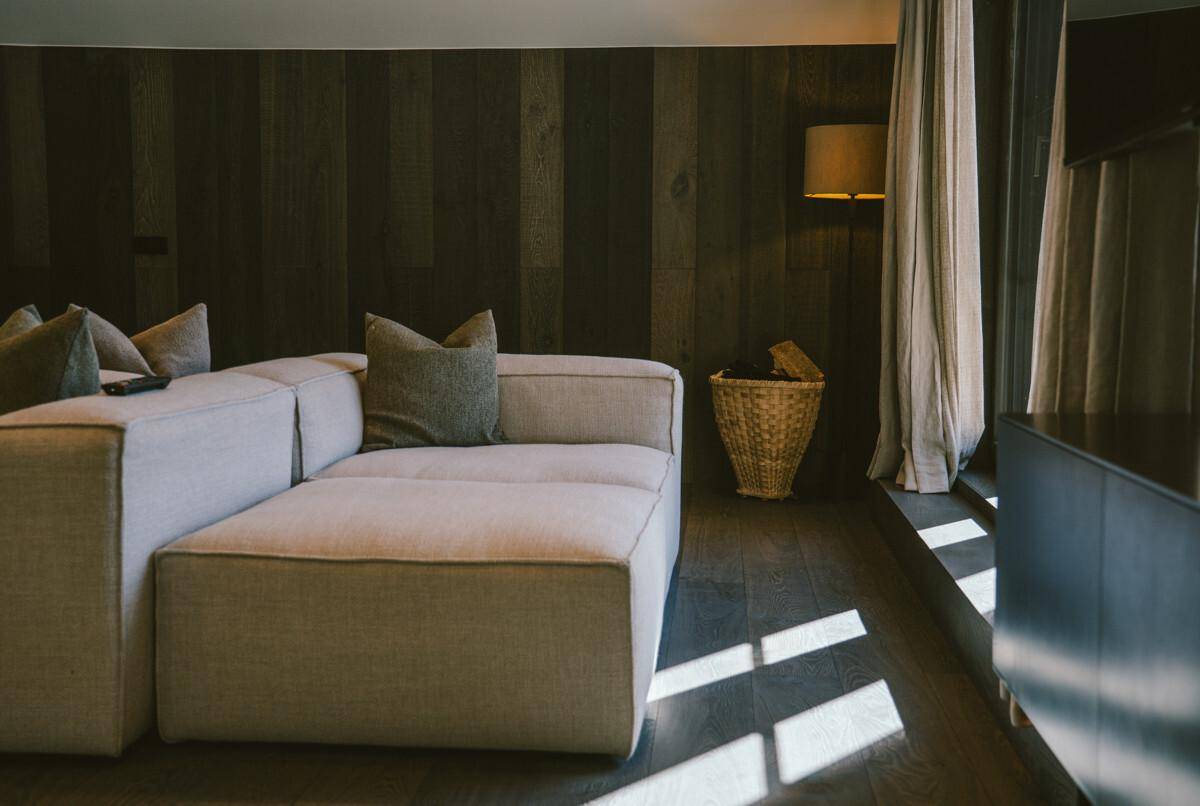 Detailansicht eines modernen Sofas in einem gemütlichen Wohnzimmer mit Holzwand.