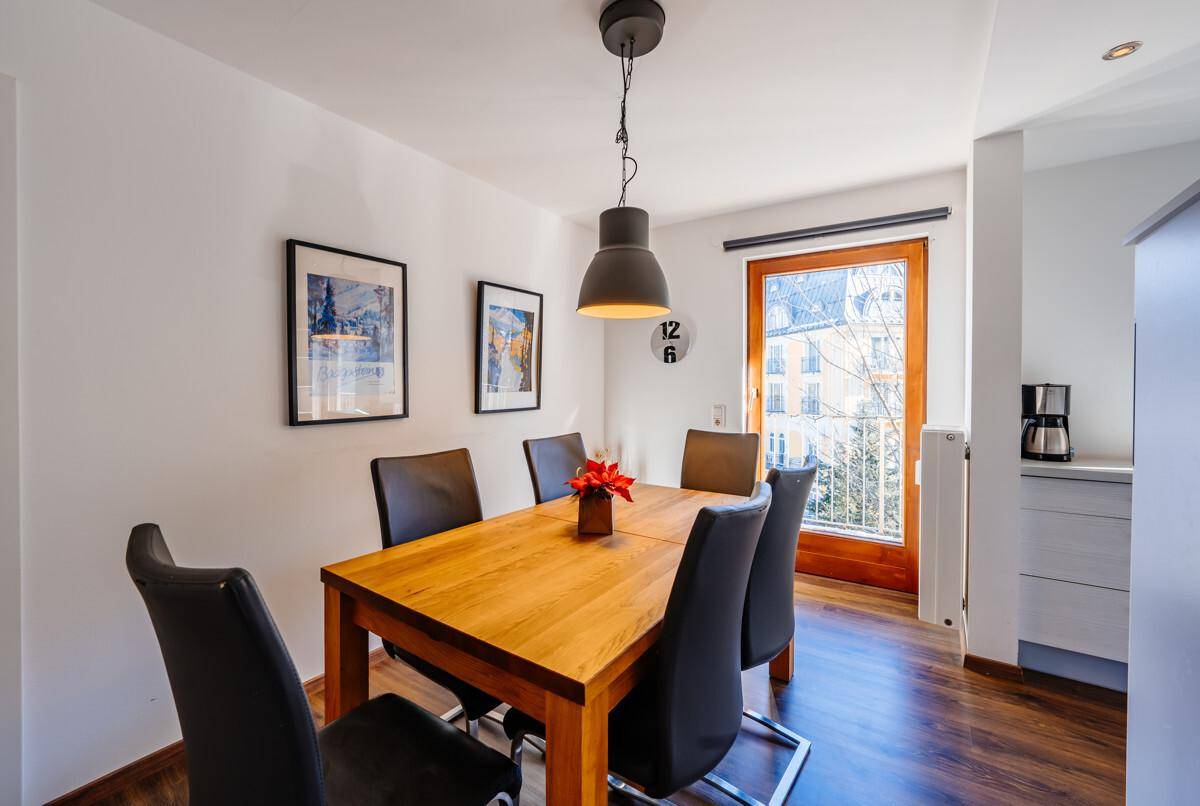 Gemütlicher Essbereich mit Holztisch, dunklen Stühlen und Zugang zu einem französischen Balkon.