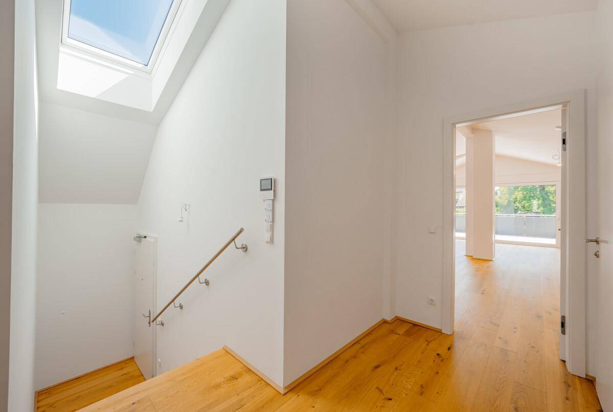 Heller Flur mit Holztreppe und einem Dachfenster, das den Bereich mit natürlichem Licht versorgt.