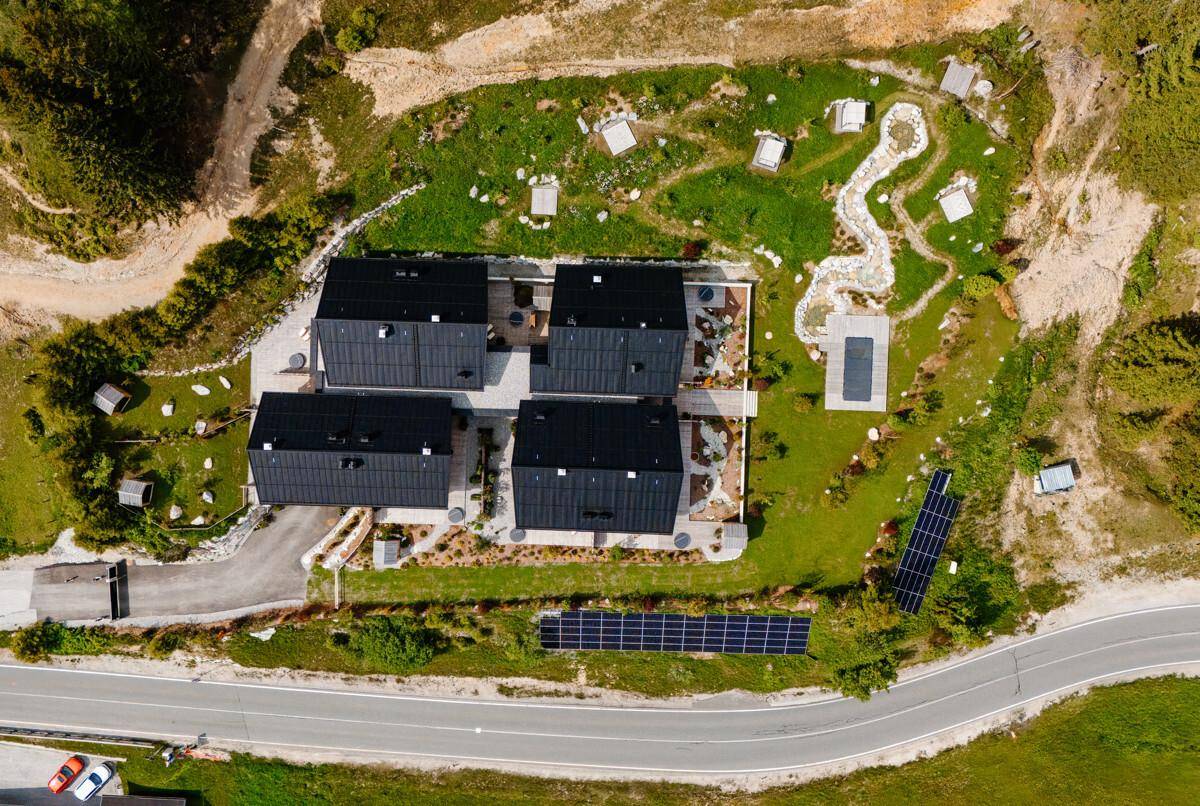 Luftaufnahme einer modernen Wohnanlage mit mehreren Gebäuden und Solaranlagen in grüner Umgebung.