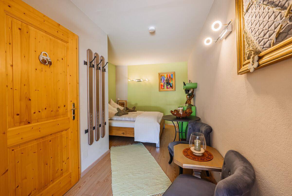 Heller Flur mit Holztür, Garderobe und Blick in ein gemütliches Schlafzimmer.