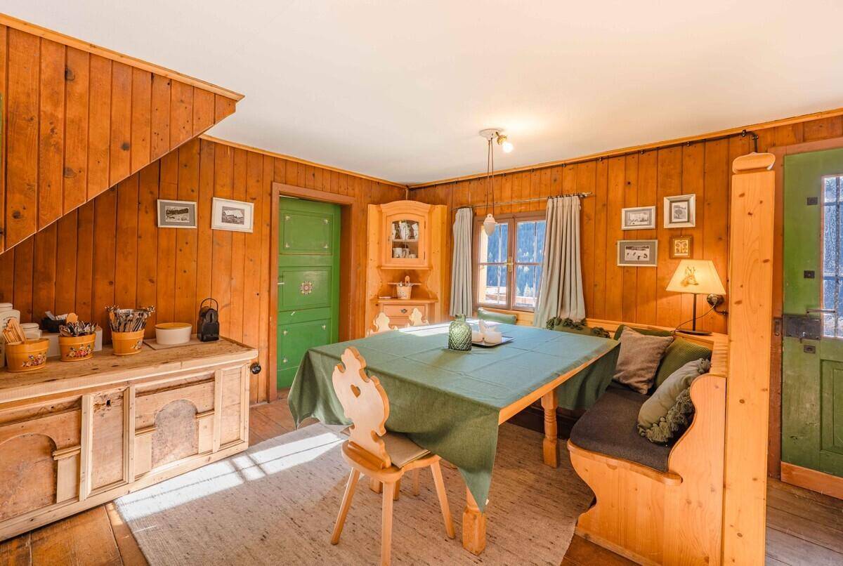 Heller Essbereich mit Holztäfelung, traditionellen Möbeln und Blick ins Grüne durch das Fenster.
