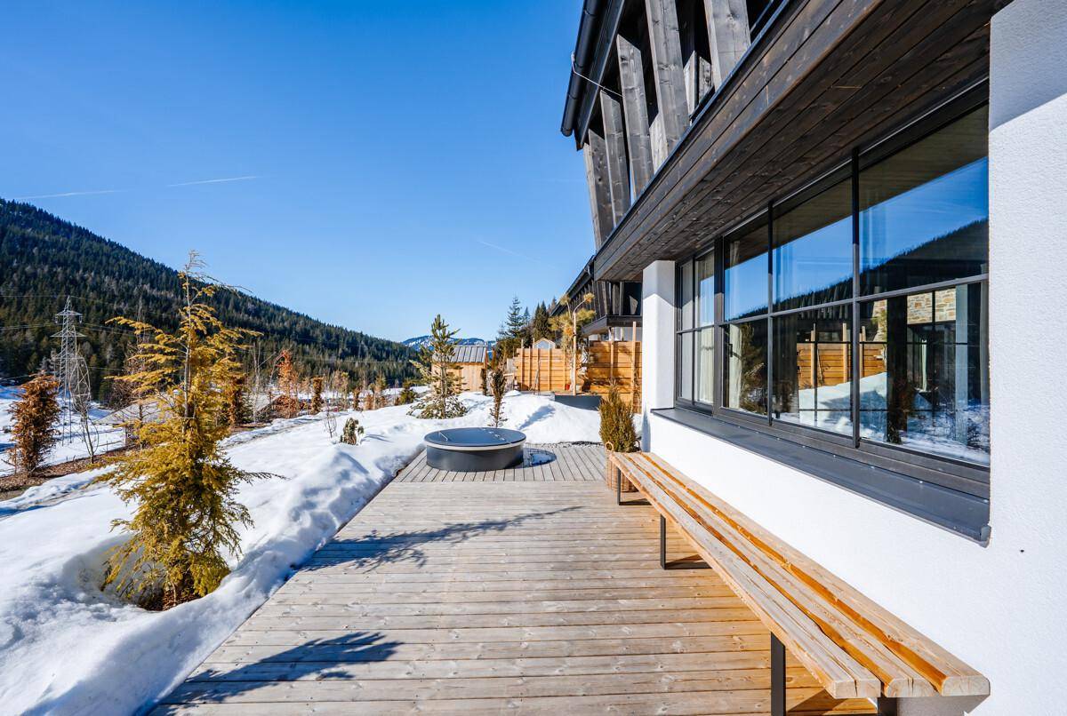 Holzterrasse mit Whirlpool und Panoramablick auf die verschneite Berglandschaft.