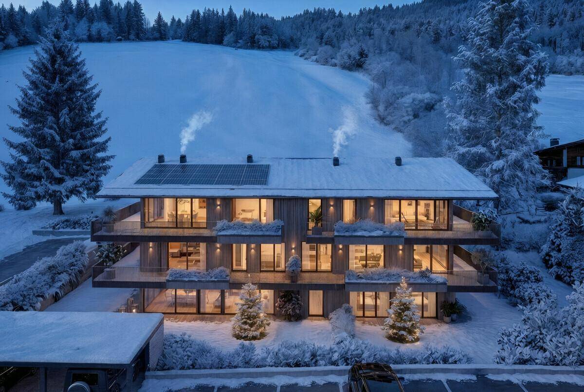 Moderne Wohnanlage im Winter bei Nacht, festlich beleuchtet mit verschneiter Landschaft.
