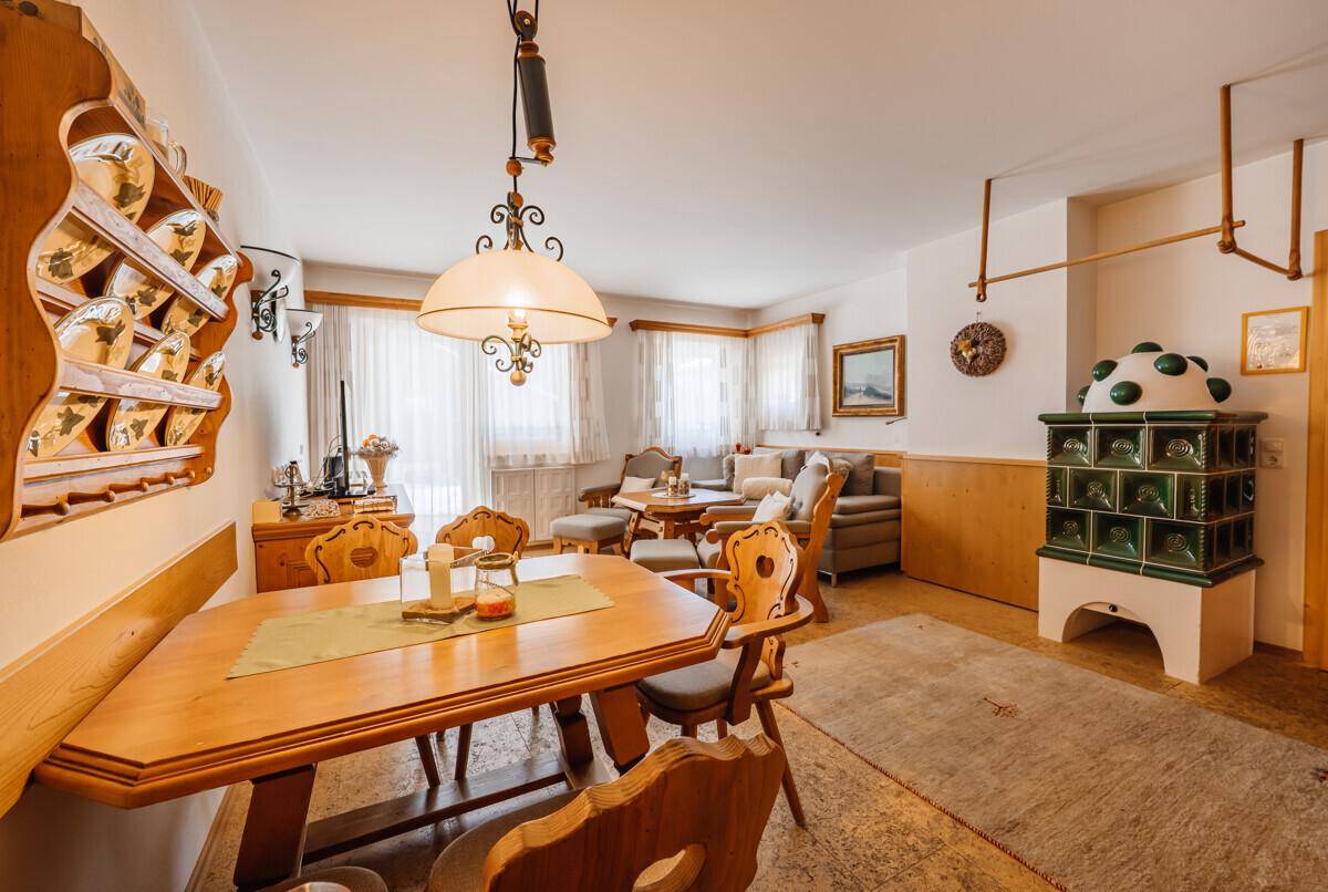 Geräumiger Essbereich mit großem Holztisch, Stühlen und einem traditionellen Kachelofen.