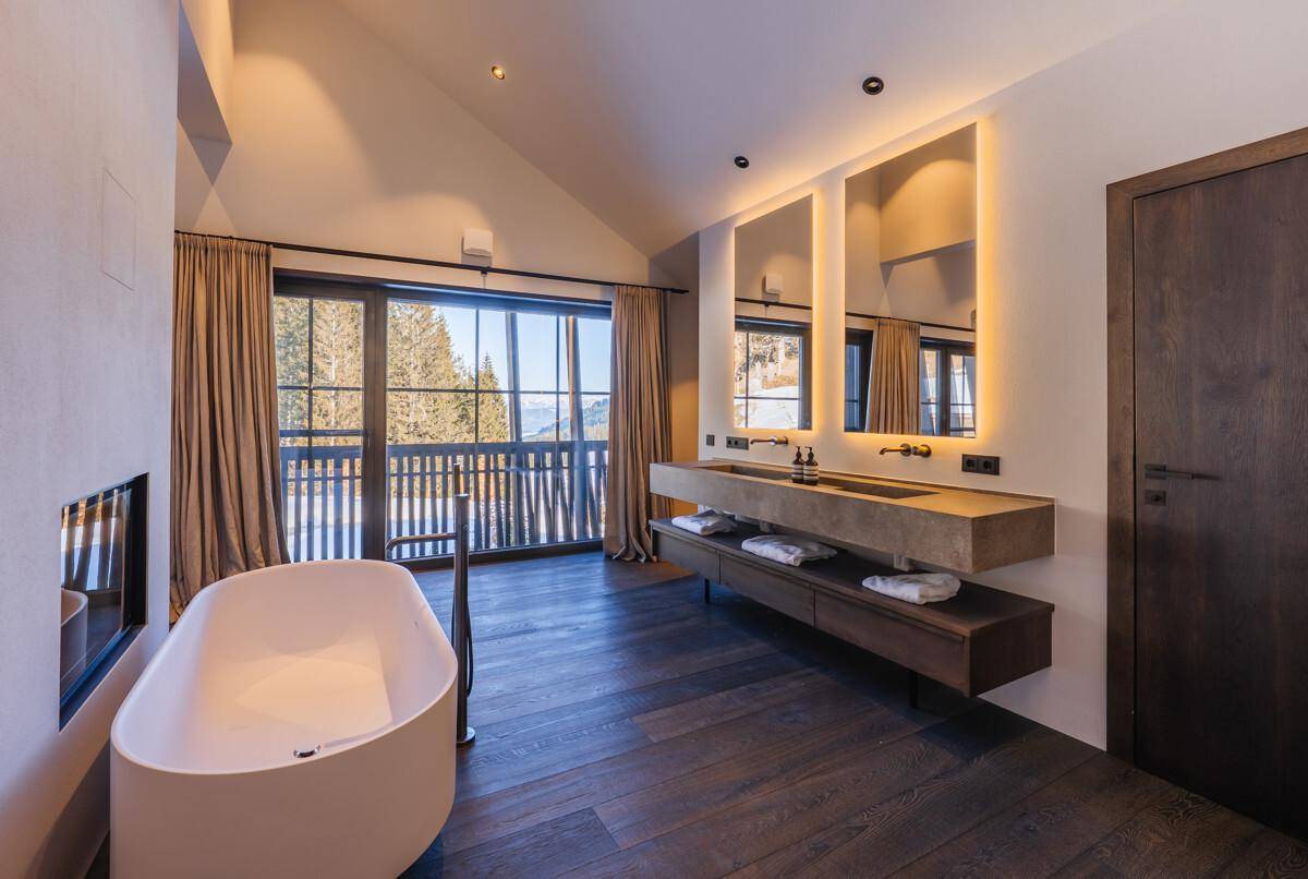 Luxuriöses Badezimmer mit freistehender Badewanne, Doppelwaschbecken und Bergblick.