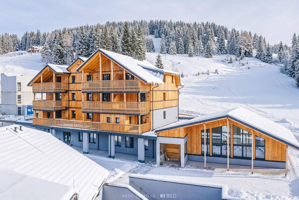Winteransicht eines modernen Apartmentkomplexes mit Holzfassade und verschneiten Dächern.