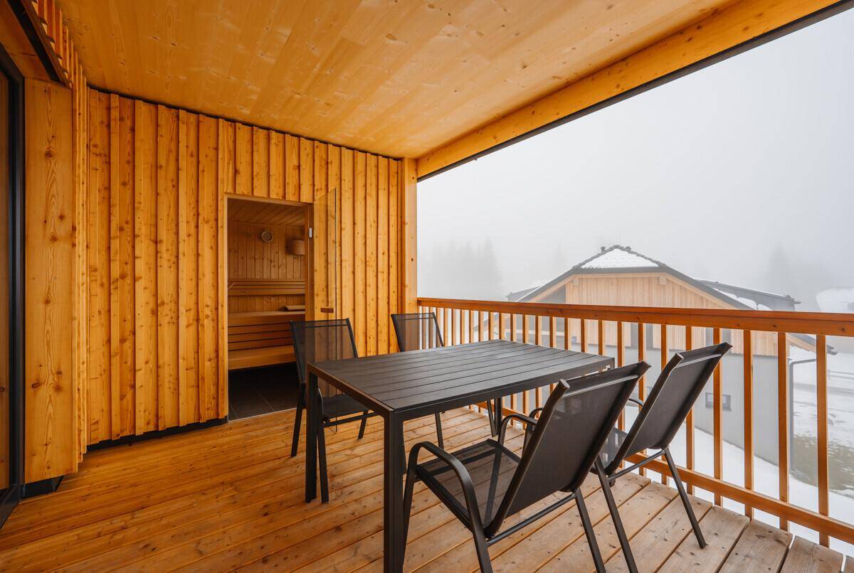 Geräumiger Balkon mit Sitzgelegenheiten und direktem Zugang zur Sauna, umgeben von Schnee.
