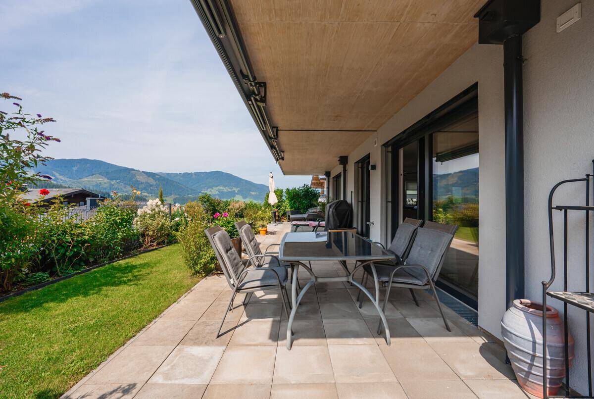 Geräumige Terrasse mit Gartenmöbeln und weitem Blick auf die umliegende Berglandschaft.