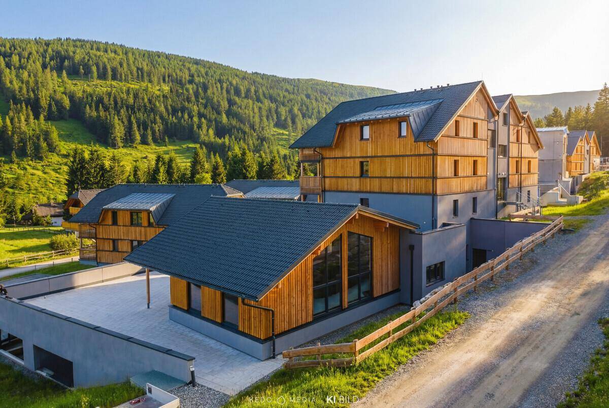 Ansicht eines modernen Apartmentgebäudes mit Holzfassade und Satteldach in bergiger Umgebung.