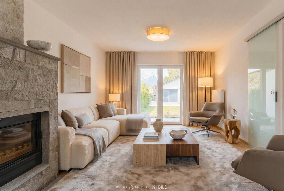 Gemütliches Wohnzimmer mit modernem Kamin, beigem Sofa und Blick auf die Berge.