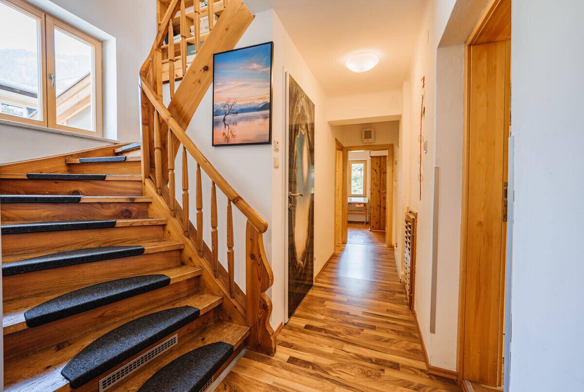 Heller Flur mit Holztreppe und passendem Holzfußboden, der zu weiteren Räumen führt.