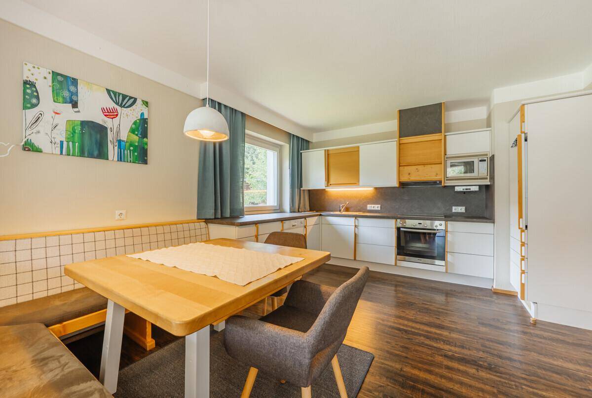 Moderne Einbauküche mit Essbereich, Holztheke und dunklem Laminatboden.
